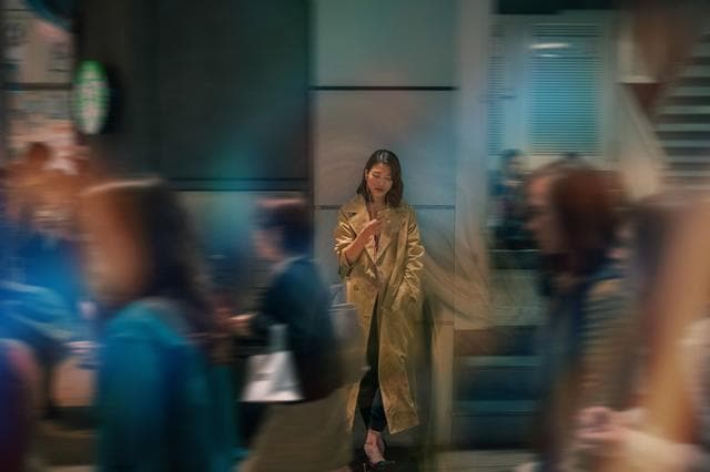 woman looking at phone in busy street people walking by