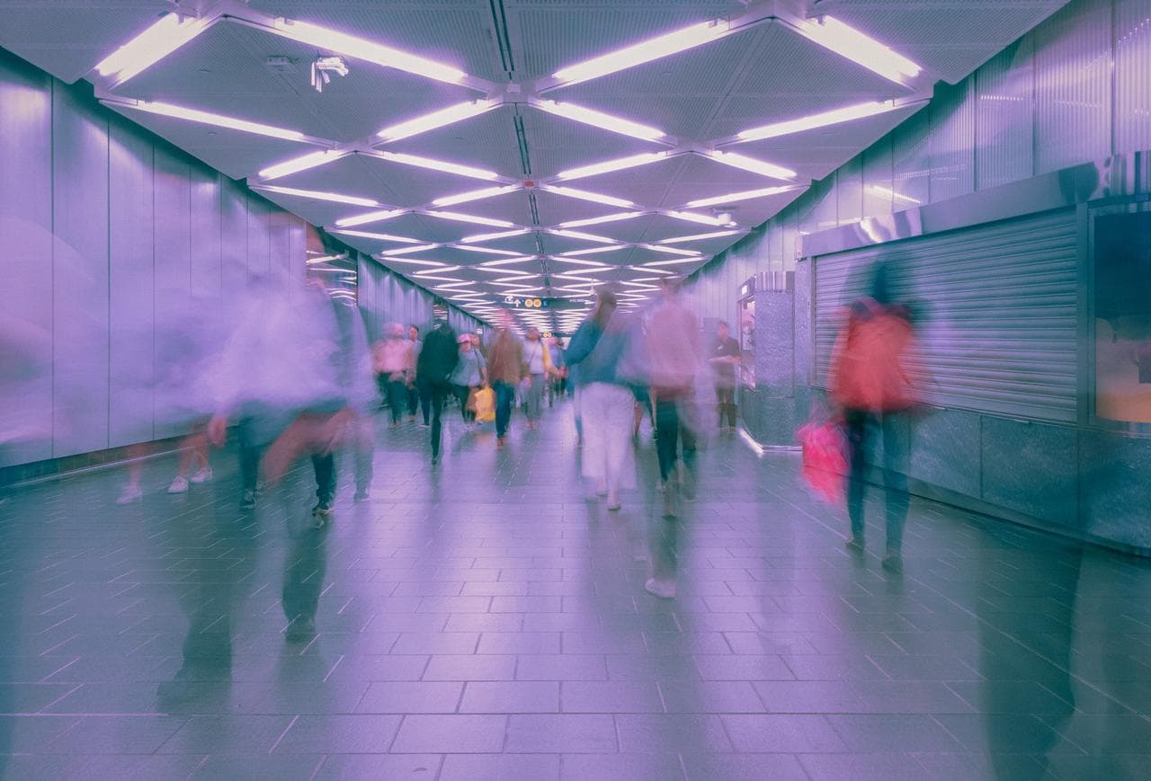 blurred image of people walking in a lighted tunnel