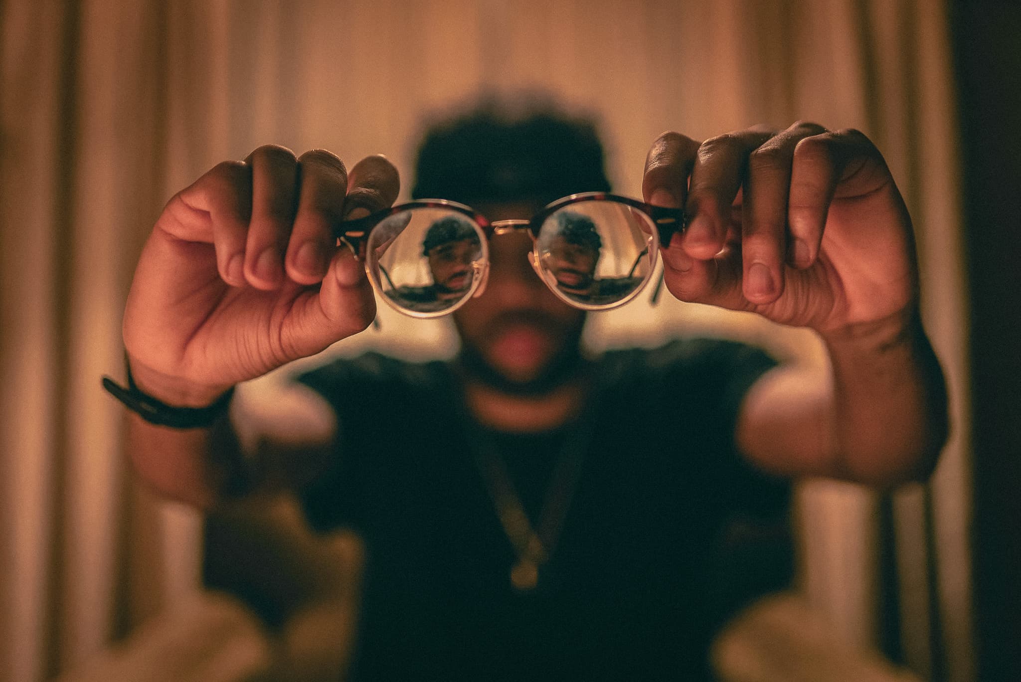 A person holding glasses away from their face.